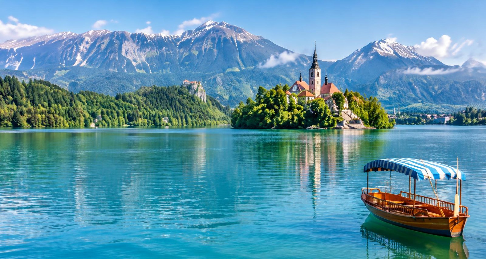 Traditional boat on Lake Bled with an island church and Alpine mountains in Slovenia